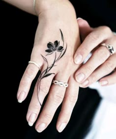 a woman's hand with a flower tattoo on her left wrist and two rings