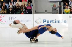 two people on skates in front of an audience at a skating rink with spectators watching