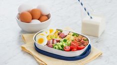 eggs, ham, and vegetables in a bowl next to a carton of milk