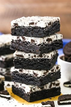 a stack of brownies with white frosting and oreo cookies in the background