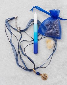 a blue bag with a pen, necklace and pendant on it sitting on a white surface