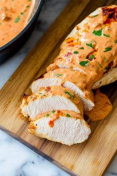 sliced chicken with sauce and garnish on a cutting board