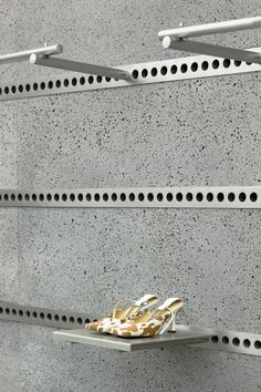 a pair of shoes sitting on top of a white shelf next to a gray wall