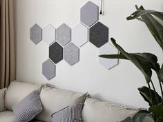 a living room with white couches and grey hexagonal tiles on the wall