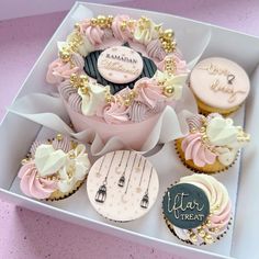 cupcakes decorated with pink and white icing in a box on a table