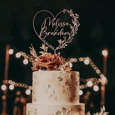 a three tiered wedding cake with a heart shaped topper and flowers on it