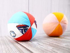 two colorful beach balls sitting on top of a wooden table next to each other,