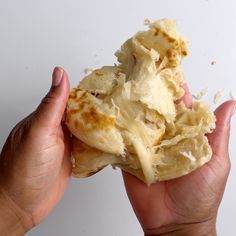 a person holding some kind of food in their hands with other hand on the table