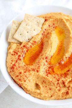 a white bowl filled with hummus and crackers