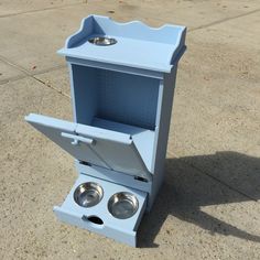 a small blue cabinet with two bowls on it's sides and the door open