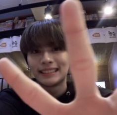 a young man making the v sign with his hand while standing in front of him