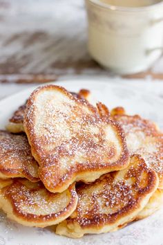 a stack of pancakes on a plate with powdered sugar