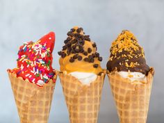 three ice cream cones with sprinkles and toppings on them are lined up