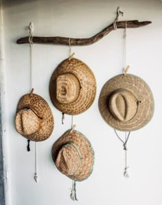 three straw hats hanging from hooks on a wall