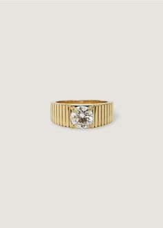 a gold ring with a white diamond in the center and two rows of stripes around it