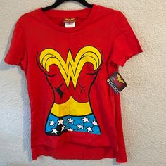 a women's red wonder woman t - shirt hanging on a wall with a tag