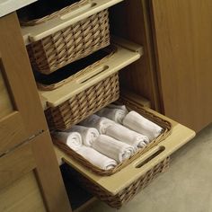 two wicker baskets with towels in them sit on the bottom shelf of a cabinet