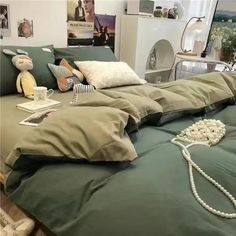 a bed with green sheets and pillows on top of it in a room filled with pictures