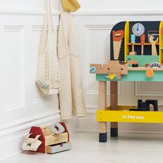 a child's wooden toy workbench with toys on the floor next to it