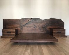 a bed made out of wood sitting on top of a hard wood floor next to a wall