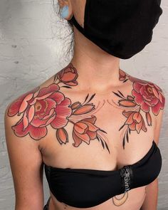 a woman wearing a black mask with red flowers on her chest and behind her head