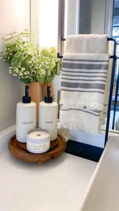 a bathroom sink with soap and lotion bottles on it next to a towel rack