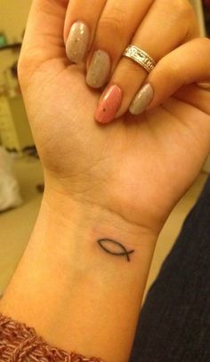 a woman's wrist with a small fish tattoo on her left hand and an arrow in the middle