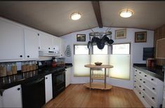 a kitchen with white cabinets and black counter tops is seen in this image, there are lights on above the stove