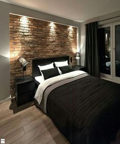 a bedroom with a brick wall behind the bed and wooden flooring is lit by recessed lights