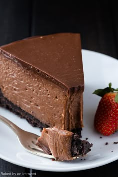 a piece of chocolate cheesecake on a plate with a fork next to it and a strawberry