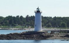 a white light house sitting on top of a small island in the middle of a lake