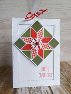 a christmas ornament hanging on a wooden table with red and green plaid ribbon