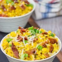 two bowls filled with corn and bacon on top of a table next to another bowl