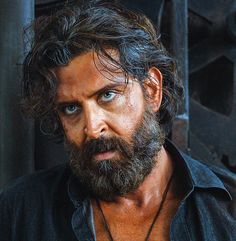 a close up of a man with a beard and blue eyes wearing a black shirt