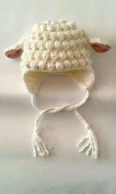 a crocheted sheep hat is shown on a white surface