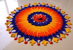 an orange, blue and yellow circular design on a white floor with a candle in the center