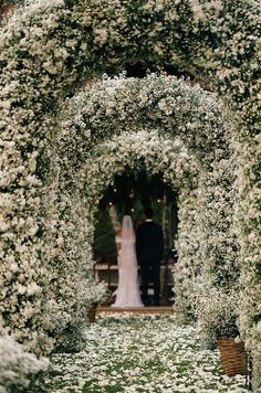 a bride and groom are standing in the middle of an archway covered with white flowers