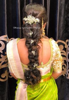 a woman with long hair wearing a green sari and flower in her hair, looking back