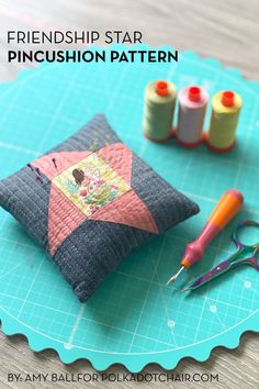 a pin cushion sitting on top of a table next to scissors and thread