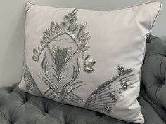 a pillow with silver sequins on it sitting on a chair next to a wall