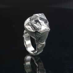 a silver ring sitting on top of a black table next to a glass surface with reflection