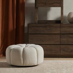 a white ottoman sitting on top of a wooden dresser