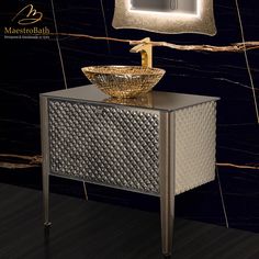 a bathroom vanity with a gold bowl sink and mirror on the wall above it, in front of a black marble background