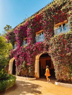 a woman walking past a building covered in flowers