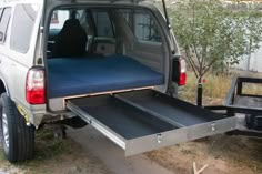 the back end of a silver van with a bed on it's flatbed