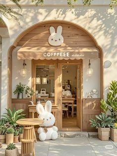 a coffee shop with large bunny statues in front of the door and potted plants outside