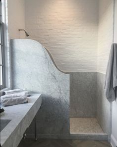 a bathroom with white walls and marble counter tops, along with a large window that looks out onto the outside