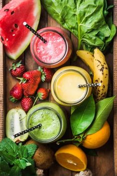 various fruits and vegetables are arranged on a wooden table with smoothies in glasses, watermelon, bananas, strawberries