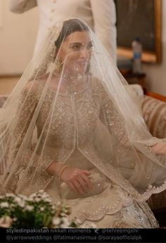 a woman wearing a veil sitting on top of a couch next to a man in a suit