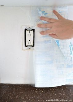 a person's hand is on top of a piece of paper with an electrical outlet attached to it